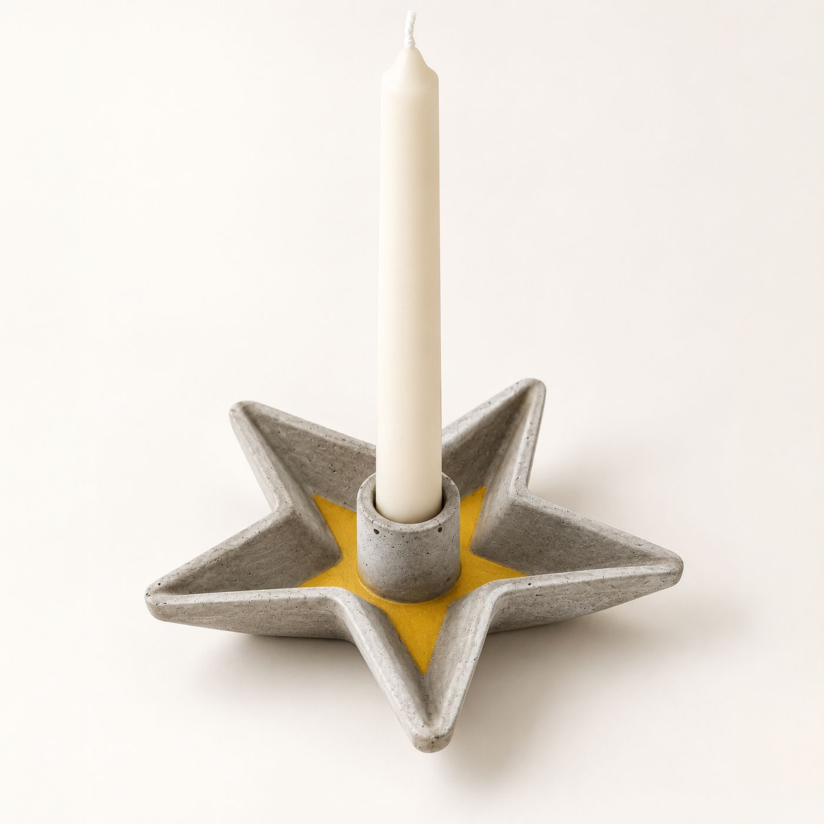 Star-shaped concrete candle holder with gold star and taper candle