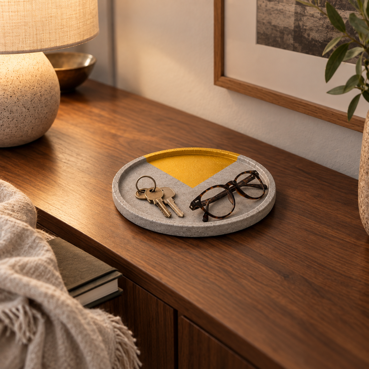 Large round concrete coaster with gold-tone circle segment used as a tray in an entryway