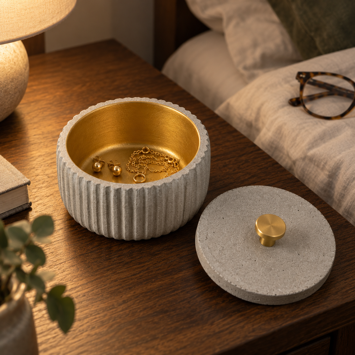 Fluted concrete canister with gold-tone interior used for jewelry on a bedside table in the evening