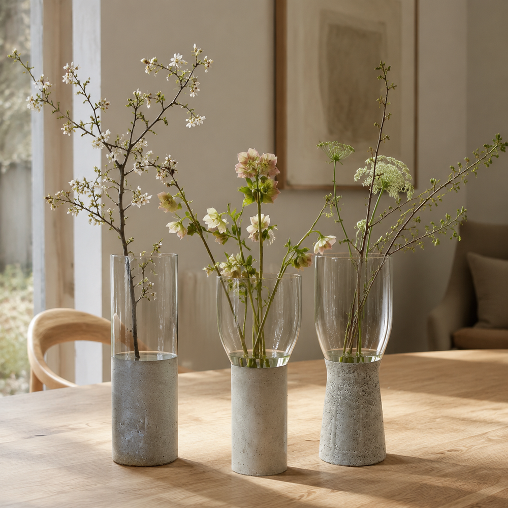 Three glass vases with concrete bases on a wooden table
