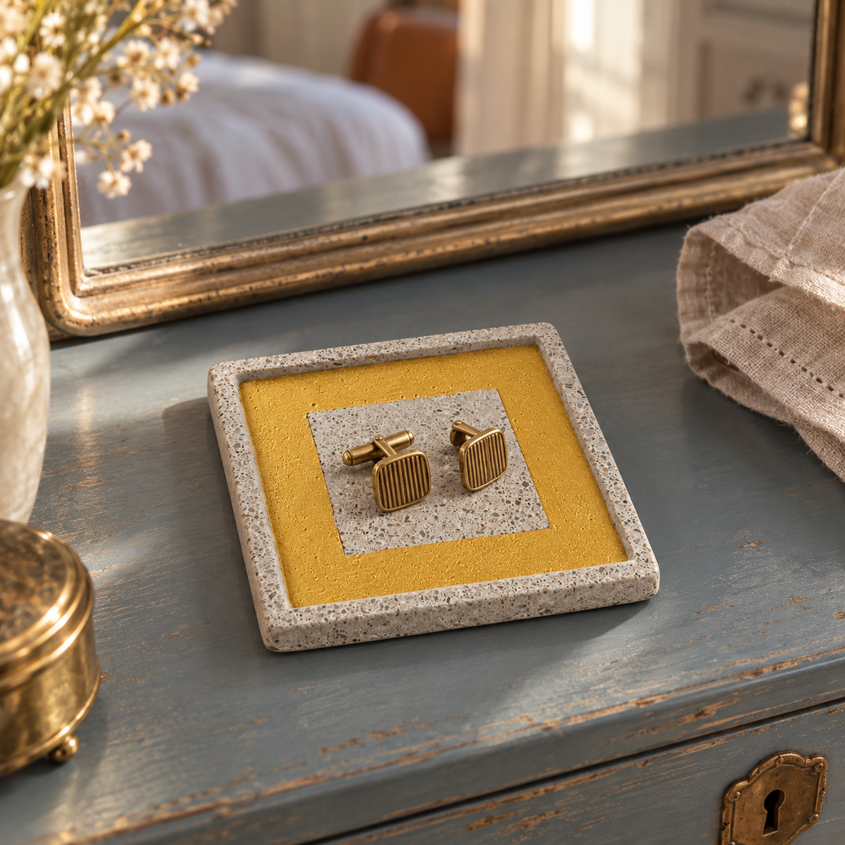 Square concrete coaster with gold-tone frame used to hold cufflinks