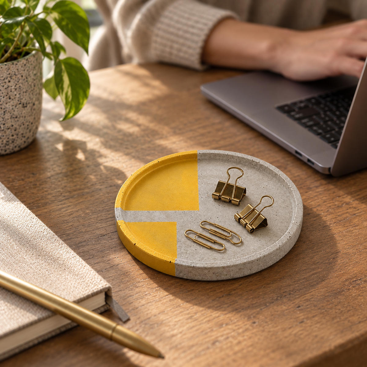 Large round concrete coaster with gold-tone sections and concrete bar on a desk