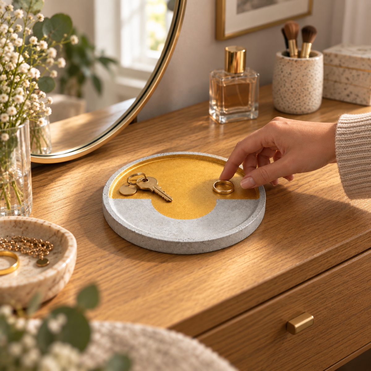 Large round concrete coaster with gold-tone arc used as a jewelry tray on a Viennese dresser