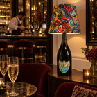 Yellow Basquiat bottle lamp in an evening bar, with a bartender in the background.