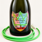 Detail of the Dom Pérignon Basquiat label with green crown, green fabric-covered cord, and white switch – AI-edited product image.