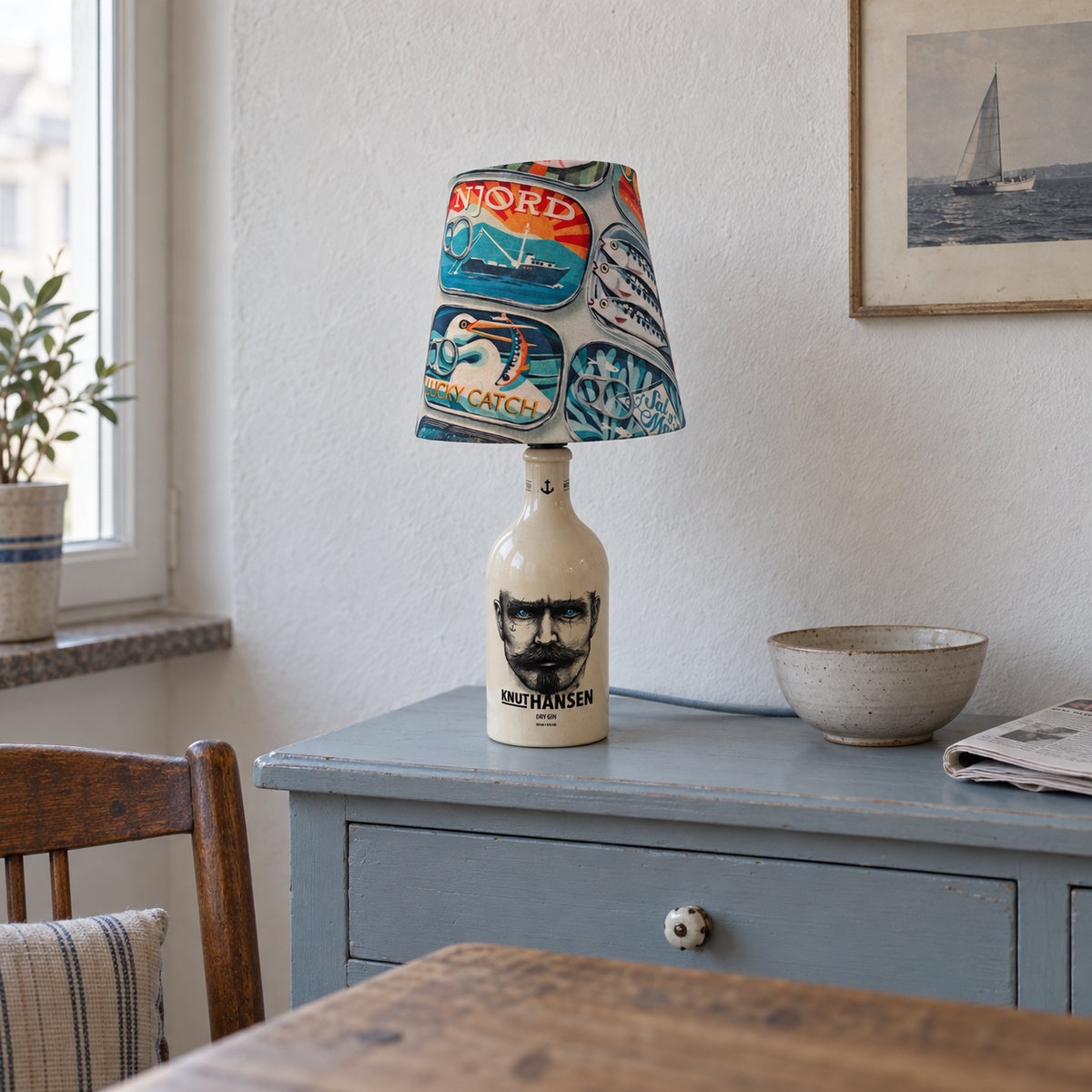 Knut Hansen Flaschenlampe ausgeschaltet auf einer hellblauen Kommode bei natürlichem Tageslicht