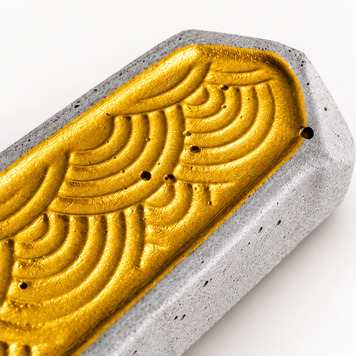 Detail der goldfarbenen Wellenstruktur und der handgefertigten Betonoberfläche der Stäbchenbank.