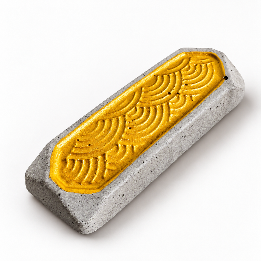 Stäbchenbank aus grauem Beton mit goldfarbenem Wellenrelief – freigestellte Gesamtansicht.