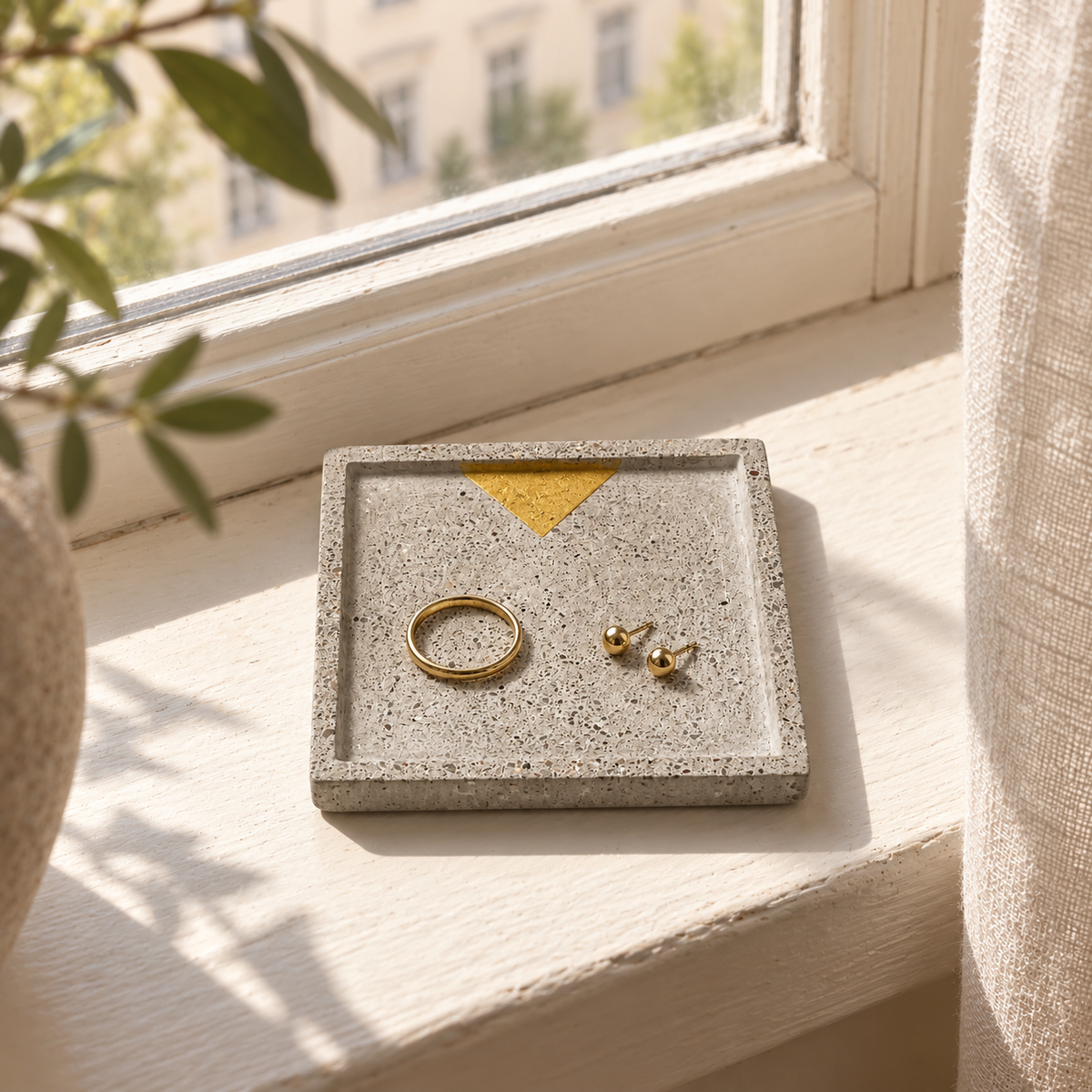 Square concrete coaster with small gold-tone triangle used as a jewelry tray